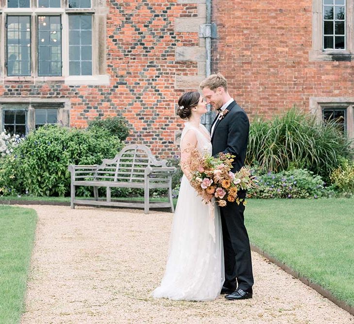 Intimate bride and groom portrait outside Dorfold Hall with bride holding a fresh and dried flower autumn bouquet 