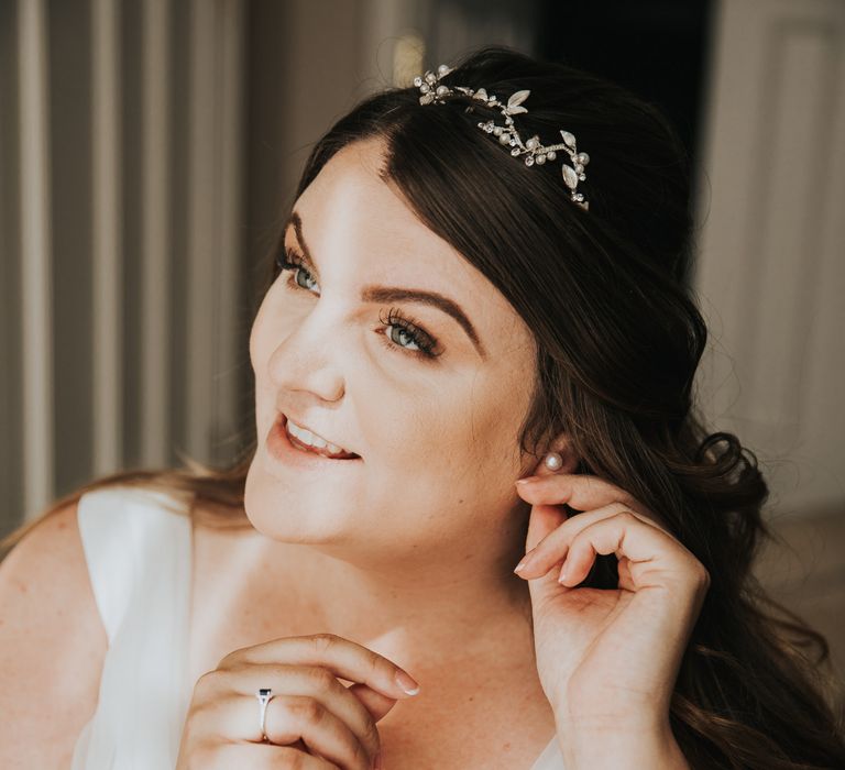 Black haired bride applies her earrings on the morning of her wedding day