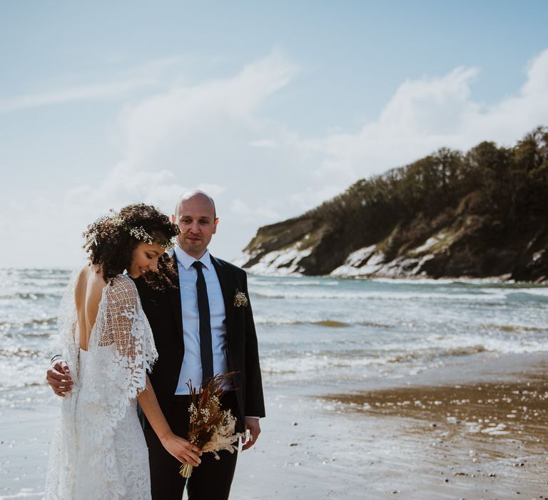 Bride & groom stroll along the beach with one another on their wedding day