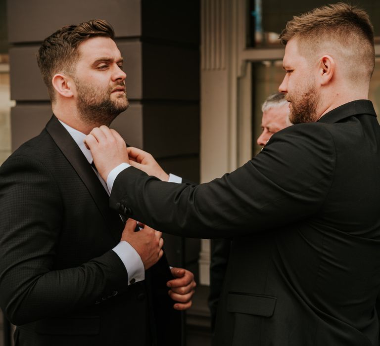 Groom in black wedding suit during preparations