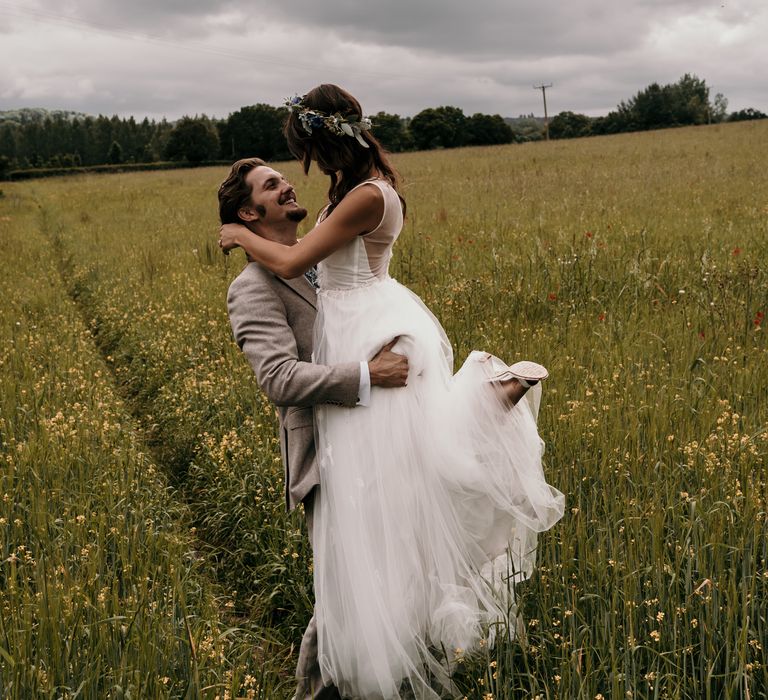 Groom picks up bride in green fields on the day of their wedding