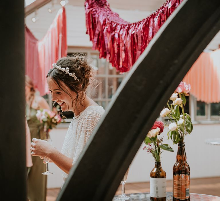 Bride laughs as she holds drink and wears bridal gown with batwing sleeve wedding gown