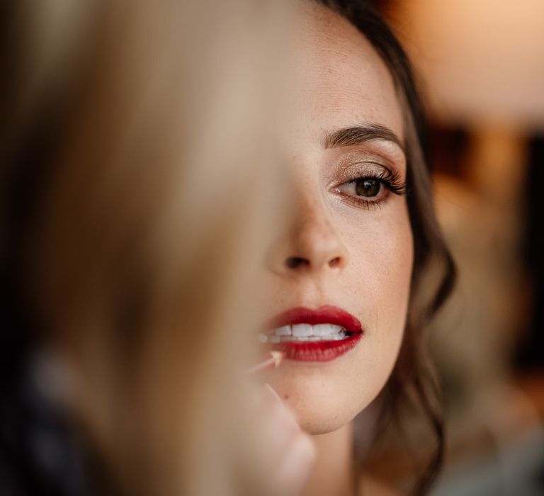 Bride with gold eyeshadow and bold red lip gets her make up done before wedding at The West Mill Derby