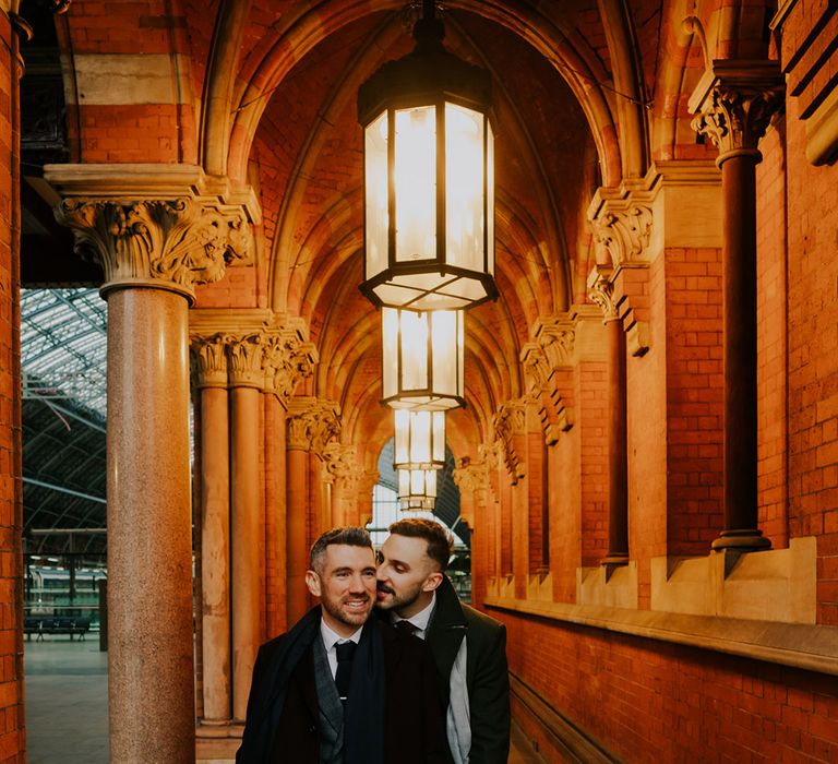 Grooms stand in brightly lit hall in St Pancreas on their wedding day