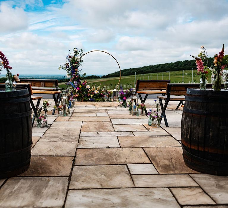 Outdoor wedding ceremony at Little Wold vineyard with wildflowers, wooden barrels and metal frame moon gate