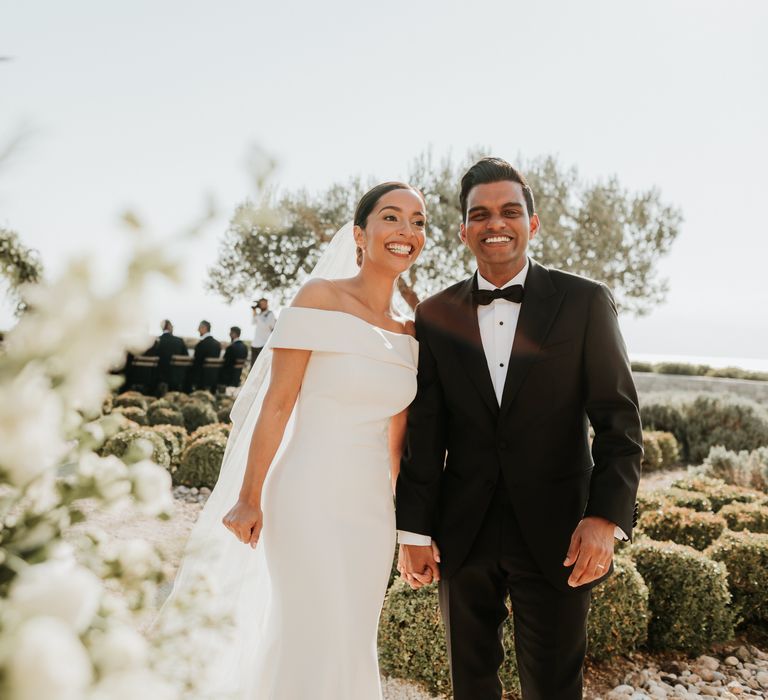 Bride leans into groom on her wedding day as they smile at the camera surrounded by white florals | Hannah MacGregor Photo & Film