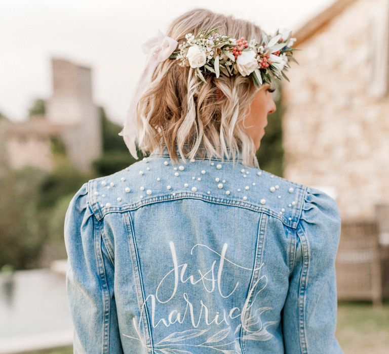 Bride with short blonde hair at destination wedding in a denim jacket with pearl and just married design on the back 