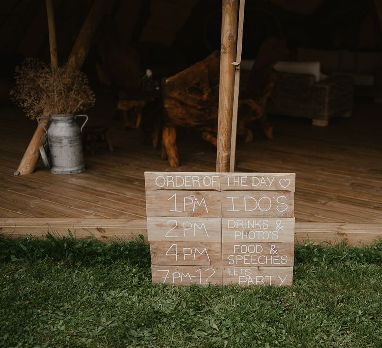 Rustic wooden order of the day sign outside of tipi at Wellington Wood Norfolk for late summer wedding