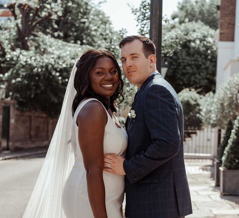 Bride & groom lean into one another on their wedding day as the sun shines around them