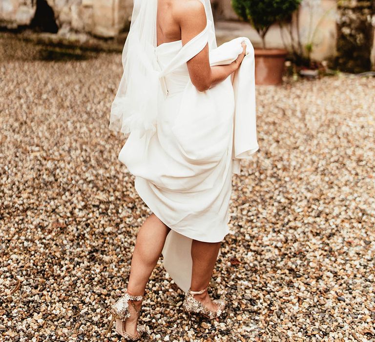 Bride lifts her gown as she walks outdoors for French wedding