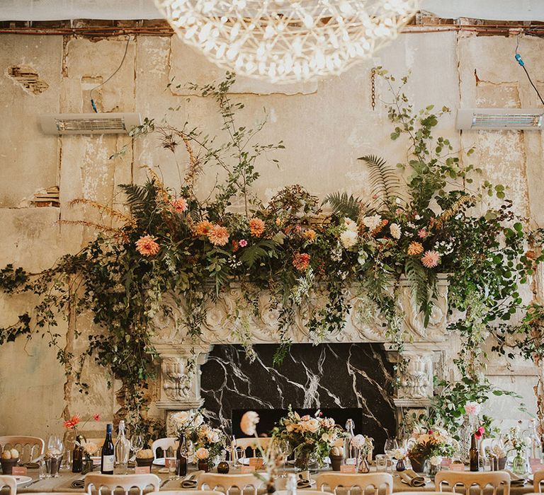 Rustic reception venue complete with large floral installation across fireplace 