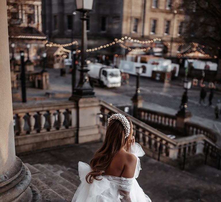 Bride sitting on the steps at St. George's Hall in Liverpool in a tulle Daniel Chu wedding dress