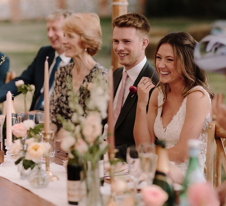 Bride and groom enjoy wedding speeches in marquee