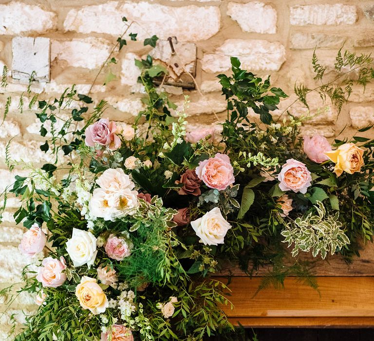 Yellow, pink and white rose floral arrangement with foliage 