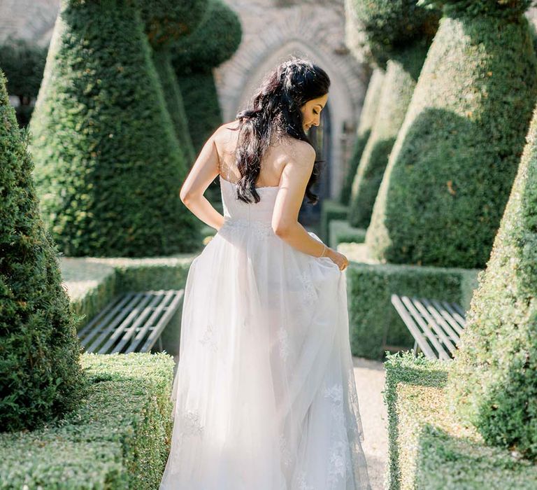 Bride walks through manicured gardens of Euridge Manor on her wedding day