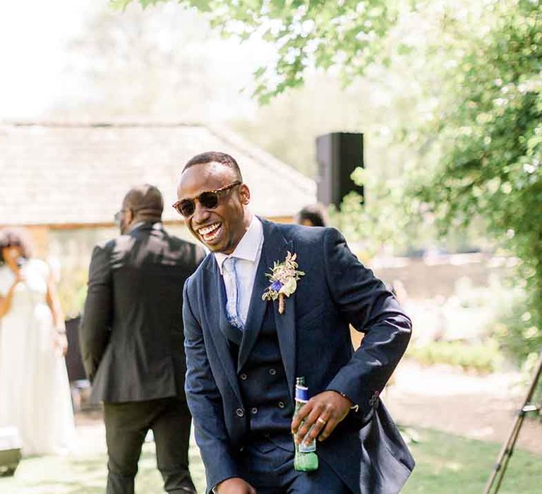 Groom wears sunglasses and three piece suit on his wedding day