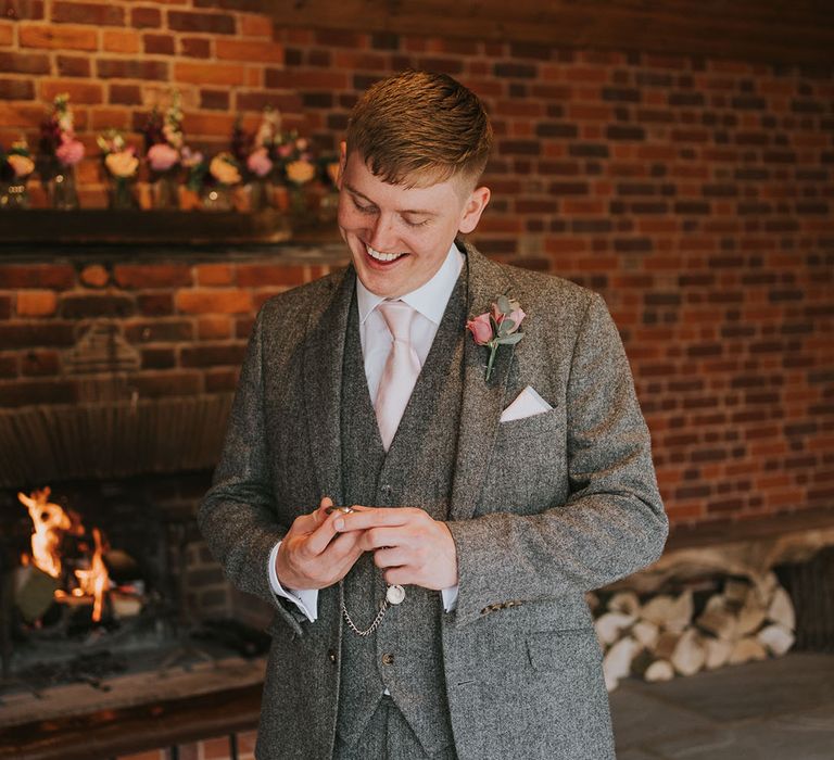 Groom in grey tweed suit with pink tie and pink rose boutonnière and silver pocket watch