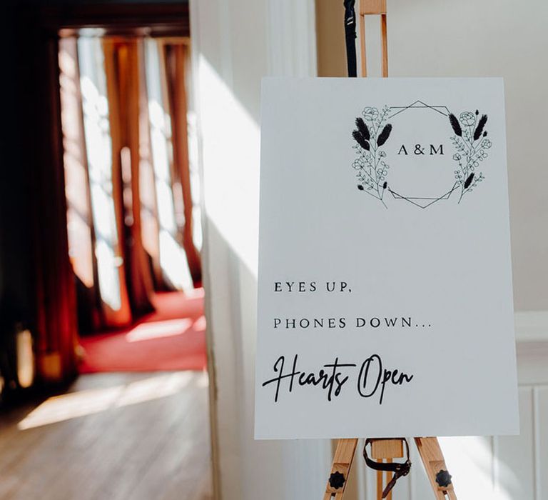 Eyes up phones down hearts open unplugged wedding sign on a wooden easel