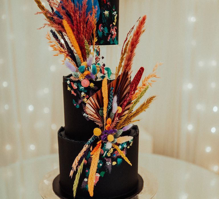 Tall three tier dark wedding cake with bright and colourful dried flower pampas grass decor 