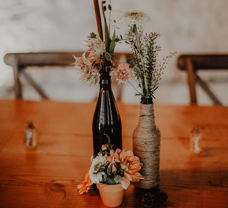 Coloured bottle vases with dried flowers and small potted plant for table decoration for wedding reception