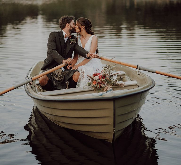 Bride and groom on a small row boat on the loch at Cardney Estate wedding venue 