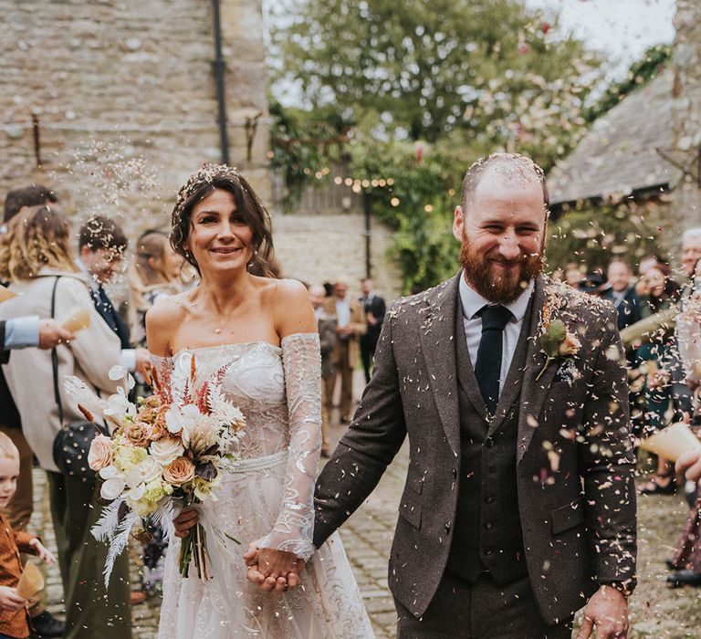 Bride and groom have their confetti exit after their ceremony with bride in Zavana Couture and groom in dark grey suit 