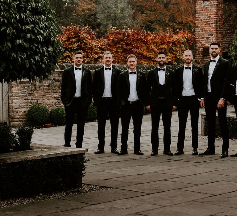 Groomsmen all in black tie for winter wedding with groom in three piece suit