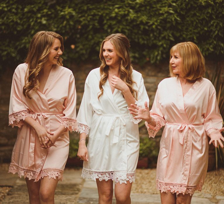 Bride with mother and sister in pink and white robes and matching slippers as they get ready for the big day 