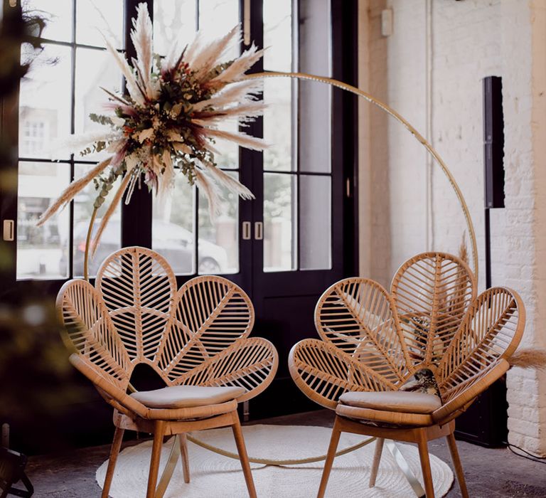 Simple moongate with small pampas grass with two rattan flower chairs 