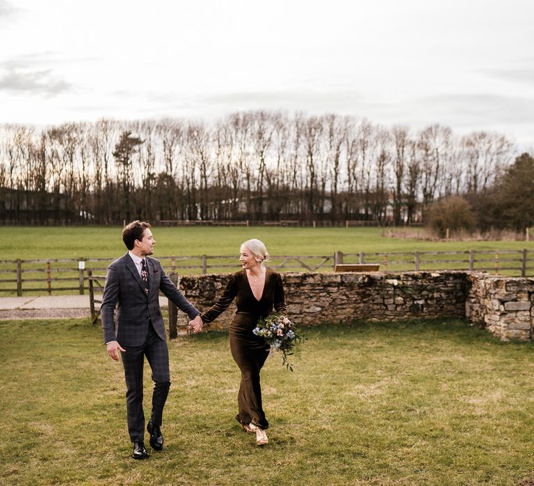 Bride & groom walk across gardens on their wedding day during relaxed couples portraits images 