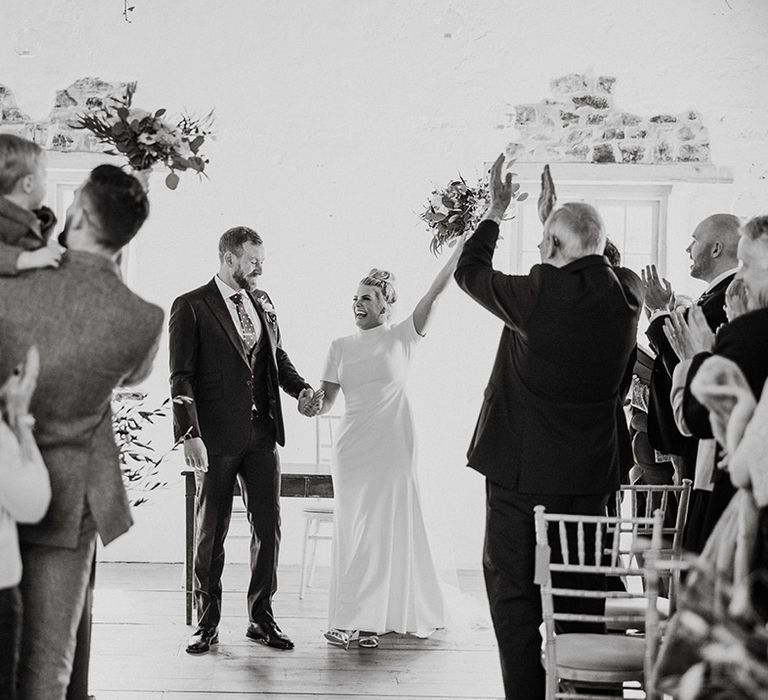 Bride and groom celebrate as they prepare to walk back down the aisle as a married couple 