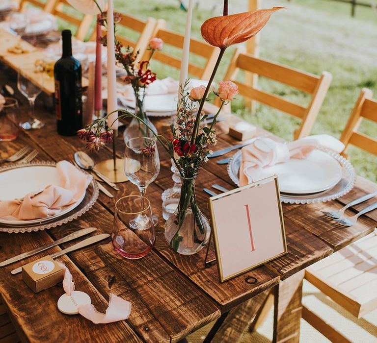 Pink taper candles, pink napkins and clear pink chargers with gold photo frame table number sign