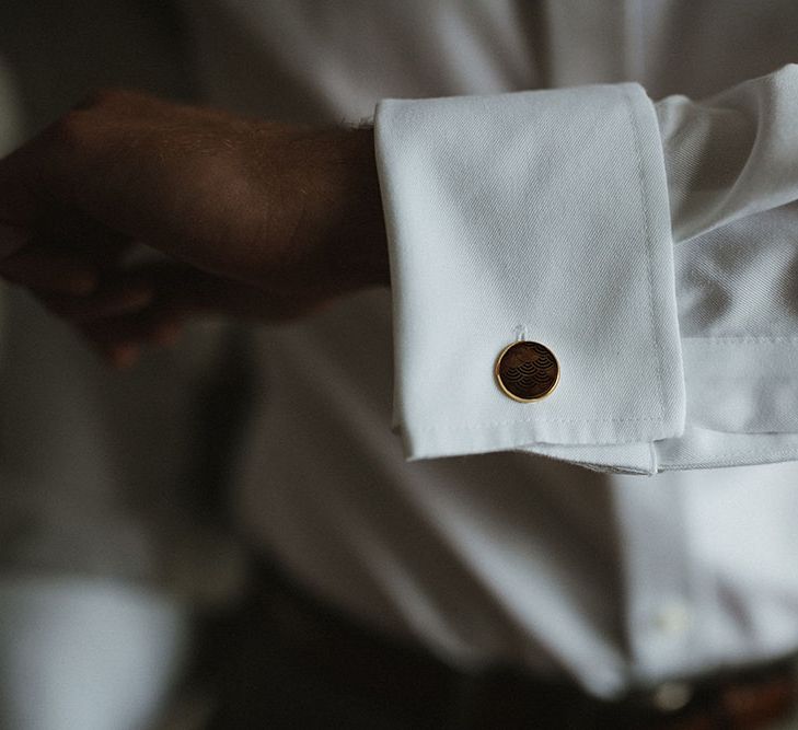 Groom wears gold cufflinks with engraved pattern to the middle 