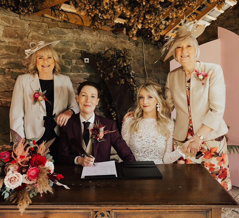 The couple sign the wedding registry with their parents watching 