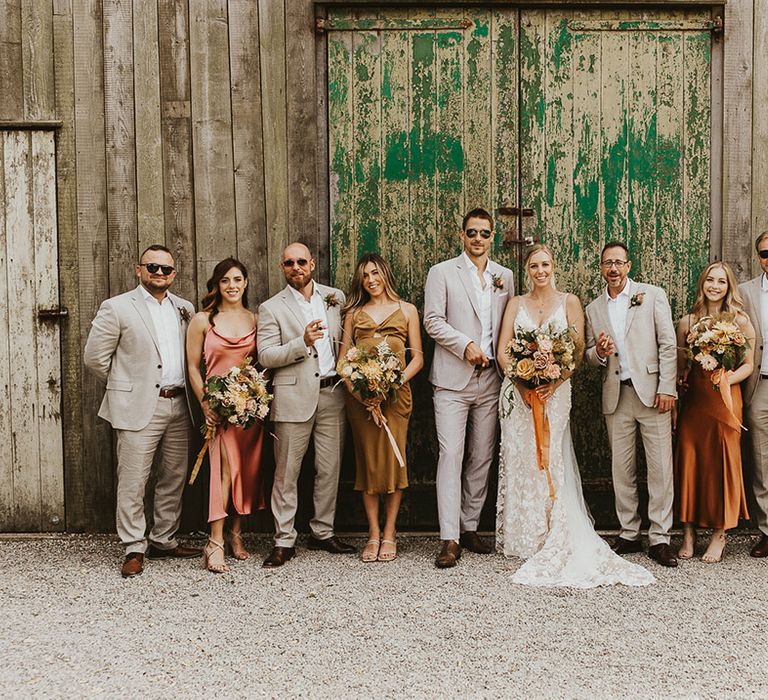 Wedding party with the groomsmen all in sunglasses and light suits and the bridesmaids in mismatched dresses