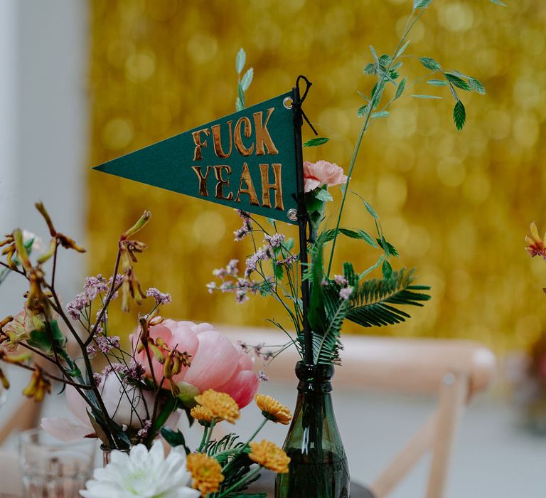 Green & gold fabric sign in thrifted vases on wooden tables with retro feel