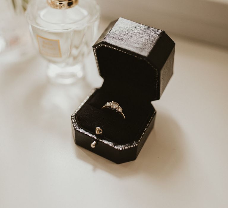 Gold and diamond trinity engagement ring in a leather ring box with her perfume 