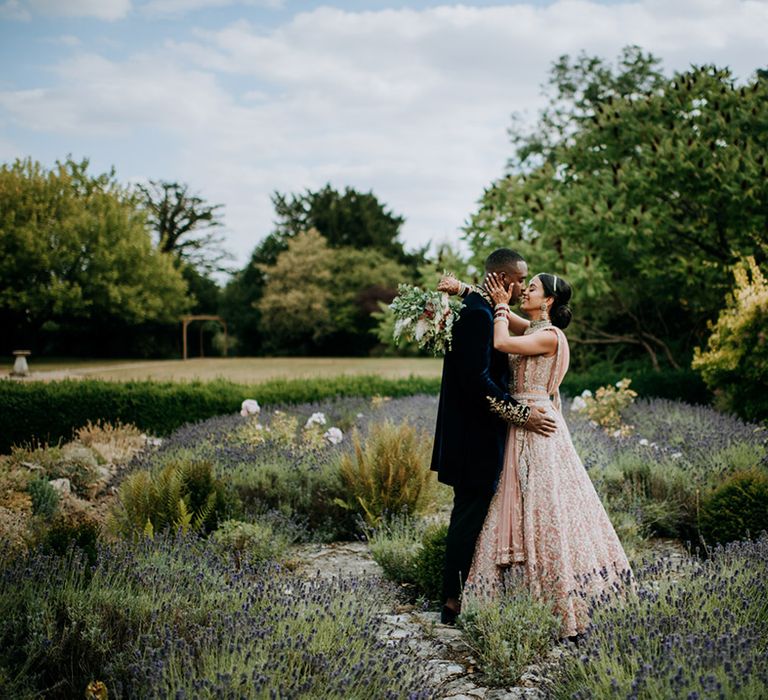 Bride and Groom pose in the grounds of Caswell House surrounded by lavender 