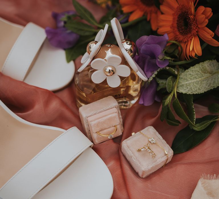 Wedding ring and jewellery beside Marc Jacobs perfume and white wedding shoes 