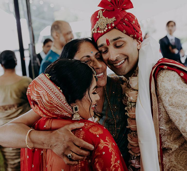 Bride & groom hug wedding guest in intimate moment after ceremony 