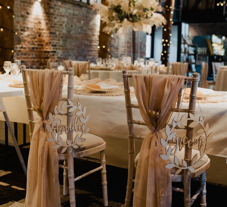 Pale pink wedding sash with wooden laser cut bride and groom signs to reserve the seats for the couple 