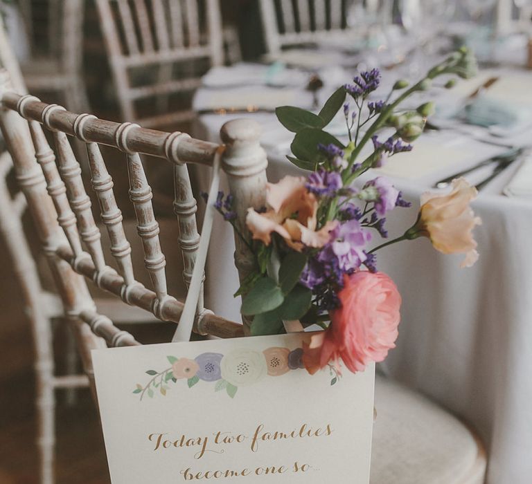 White and gold wedding sign chair decor with poppy flower motif with white ribbon and purple wedding flowers 