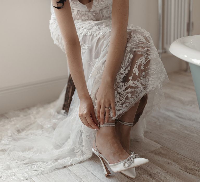 Bride in embellished flower wedding dress wearing white wedding shoes with sparkly bow detail for contemporary unique wedding 