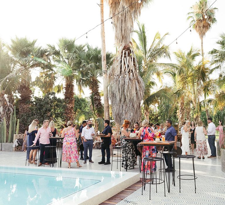 Wedding guests gather beside pool during destination wedding in Mexico 