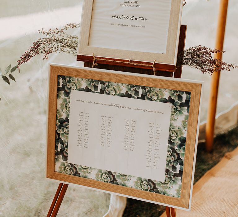 Wooden photo frames of the wedding table plan and small wedding welcome sign with leaf print design 