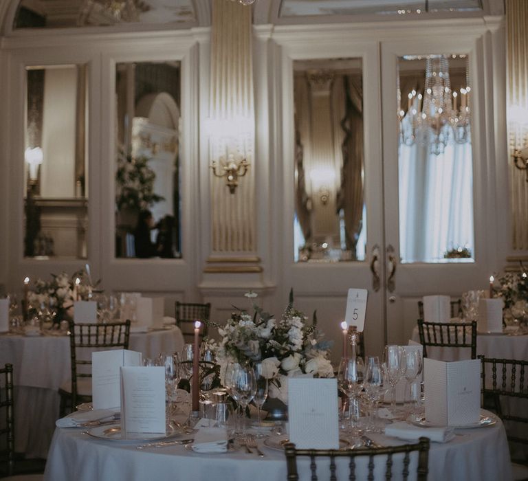 Claridge's wedding with light blue and white candles with a round wedding table with white tablecloth and table number signs 