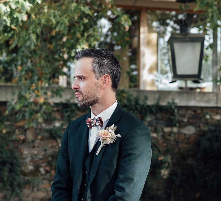 groom in a three-piece wedding suit with floral bow tie 