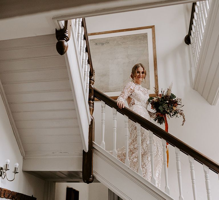 The bride descends the stairs in her Catherine Deane wedding dress as she heads to the venue 