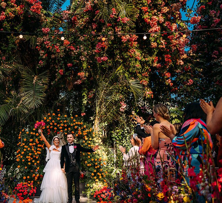 Botanical wedding at a glasshouse wedding venue with the bride and groom turning to face their guests as husband and wife 