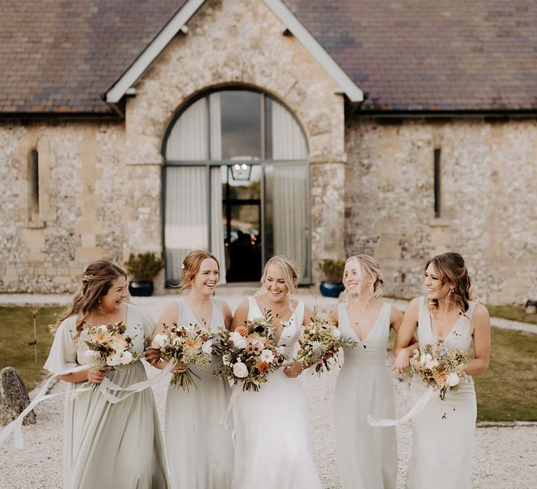 Bridal party in sage green satin bridesmaid dresses with the bride in a Maggie Sottero wedding dress at rustic barn wedding venue 